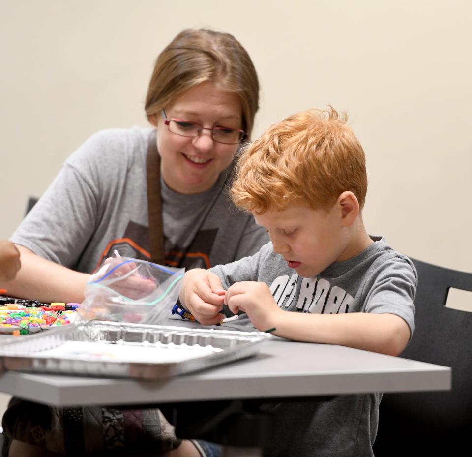 Rachel DeCapito of North Canton looks on as her son, Elijah, 5, works to make a bracelet at a Family Art Party at the North Canton Public Library.