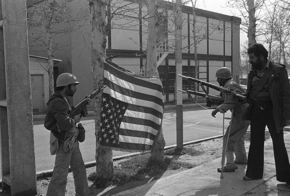 FILE - In this Feb. 12, 1979 file photo, Iranian rebels pose with a U.S. flag they bayonetted upside down on trees at Sultanabad Garrison northeast of Tehran, Iran. Monday, Feb. 11, 2019 marks the 40th anniversary of the Islamic Revolution in Iran, which overthrew the caretaker government left behind by the cancer-stricken Shah Mohammad Reza Pahlavi, who had left the country only weeks earlier. (AP Photo/Saris, File)