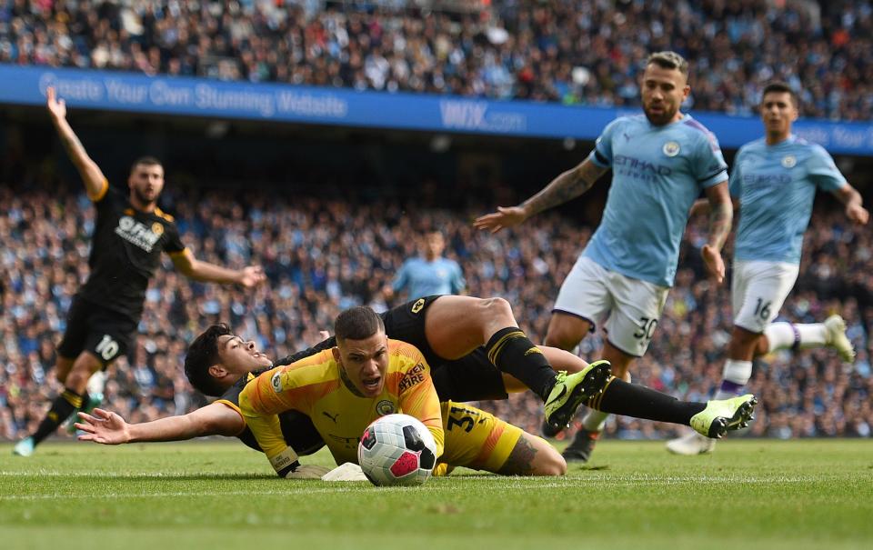 Wolverhampton Wanderers' Mexican striker Raul Jimenez lands on the back of Manchester City's Brazilian goalkeeper Ederson after the keeper made a save during the English Premier League football match between Manchester City and Wolverhampton Wanderers at the Etihad Stadium in Manchester, north west England, on October 6, 2019. (Photo by Oli SCARFF / AFP) / RESTRICTED TO EDITORIAL USE. No use with unauthorized audio, video, data, fixture lists, club/league logos or 'live' services. Online in-match use limited to 120 images. An additional 40 images may be used in extra time. No video emulation. Social media in-match use limited to 120 images. An additional 40 images may be used in extra time. No use in betting publications, games or single club/league/player publications. /  (Photo by OLI SCARFF/AFP via Getty Images)