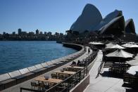 Tables at an open restaurant are seen mostly deserted on a quiet morning at the waterfront of the Sydney Opera House in Sydney