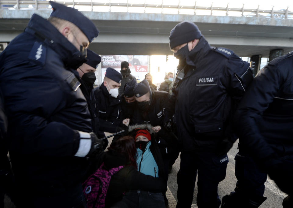 People detain a protestor during a protest on International Women's Day in Warsaw, Poland, Monday March 8, 2021. Women’s rights activists in Poland marked International Women’s Day on Monday caught between reasons to celebrate and a heavy sense that they are facing a long battle ahead. This year’s Women’s Day, which is being marked with protests, comes after a near total ban on abortion took effect in January in the historically Roman Catholic country, a step that had long been been sought by the conservative ruling party, Law and Justice. (AP Photo/Czarek Sokolowski)