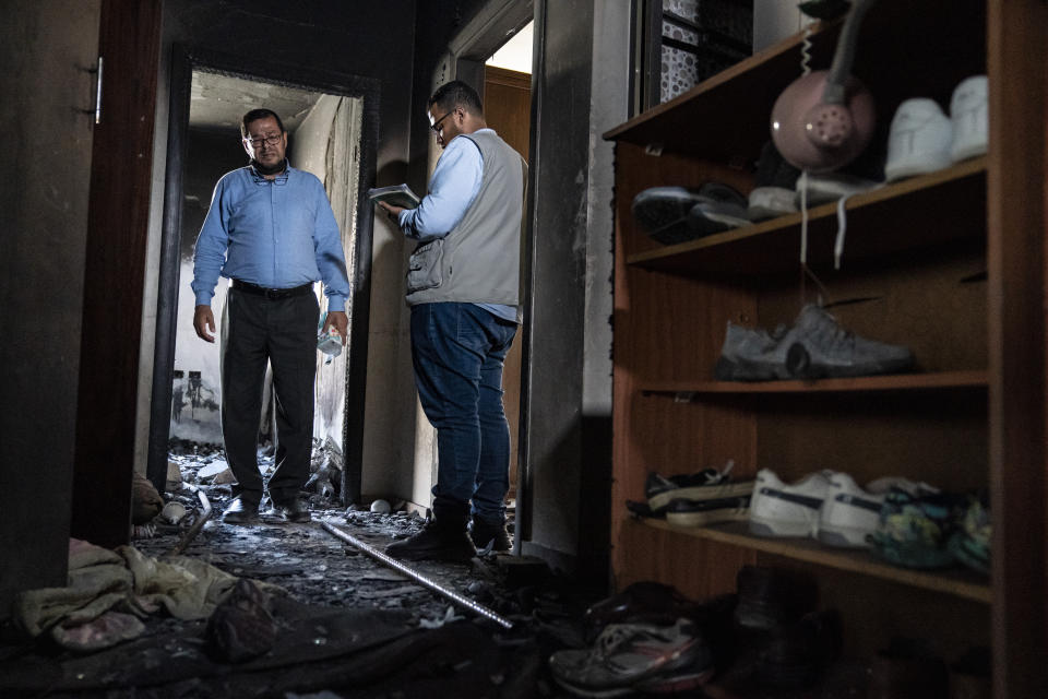 Mohammed Elfarawi, left, speaks to Khalid Sbitan, a human rights worker for Al Mezan Center for Human Rights, right, in the severely damaged room that belonged to his son Adam who was killed when an airstrike targeted the apartment below prior to a cease-fire that halted an 11-day war between Gaza's Hamas rulers and Israel, Thursday, May 27, 2021, in Gaza City. (AP Photo/John Minchillo)