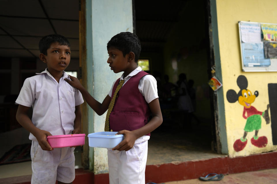 Two primary students talk after taking their free meals given as apart of a feeding program at the Dalukana Primary School in Dimbulagala, about 200 kilometres north east of Colombo, Sri Lanka, Monday, Dec. 12, 2022. Due to Sri Lanka's current economic crisis families across the nation have been forced to cut back on food and other vital items because of shortages of money and high inflation. Many families say that they can barely manage one or two meals a day. (AP Photo/Eranga Jayawardena)