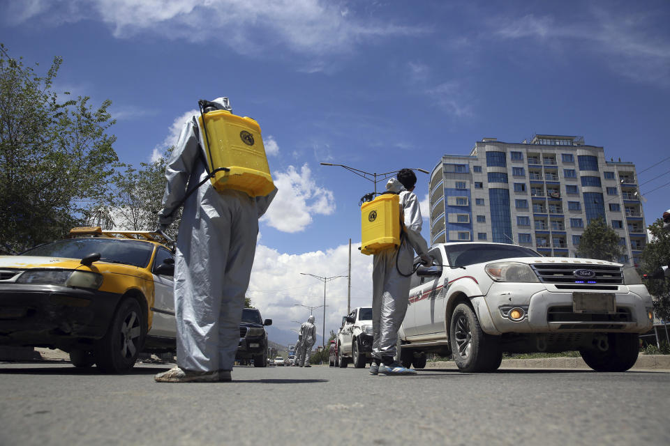 Image: Volunteers in protective suits spray disinfectant on passing vehicles to help curb the spread of the coronavirus in Kabul, Afghanistan (Rahmat Gul / AP)