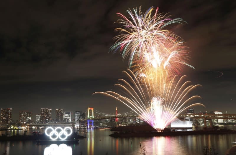 Fireworks light up the sky near the illuminated Olympic rings at a ceremony to mark six months before the start of the 2020 Olympic Games in Tokyo