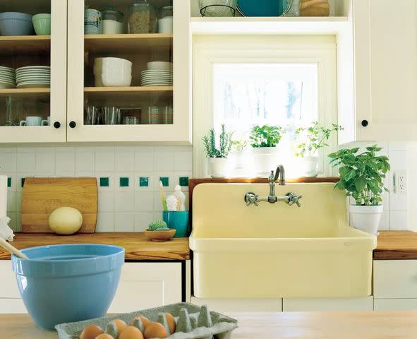 <p>ERIK JOHNSON</p> This modern kitchen features a butter yellow sink reminiscent of 1940s color palettes.