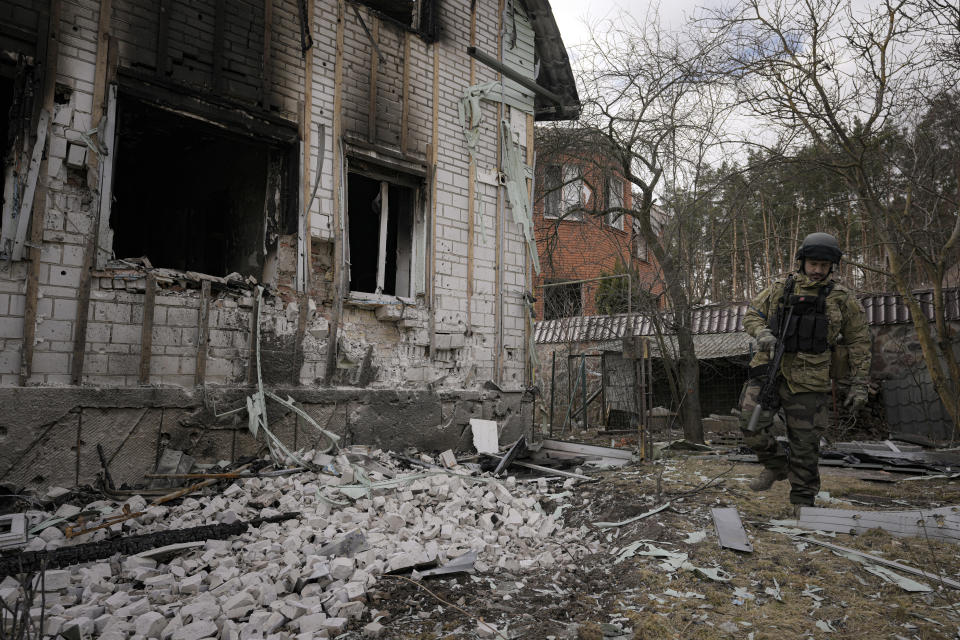 A Ukrainian serviceman walks by a heavily damaged building in Stoyanka, Ukraine, Sunday, March 27, 2022. Ukrainian President Volodymyr Zelenskyy accused the West of lacking courage as his country fights to stave off Russia's invading troops, making an exasperated plea for fighter jets and tanks to sustain a defense in a conflict that has ground into a war of attrition. (AP Photo/Vadim Ghirda)