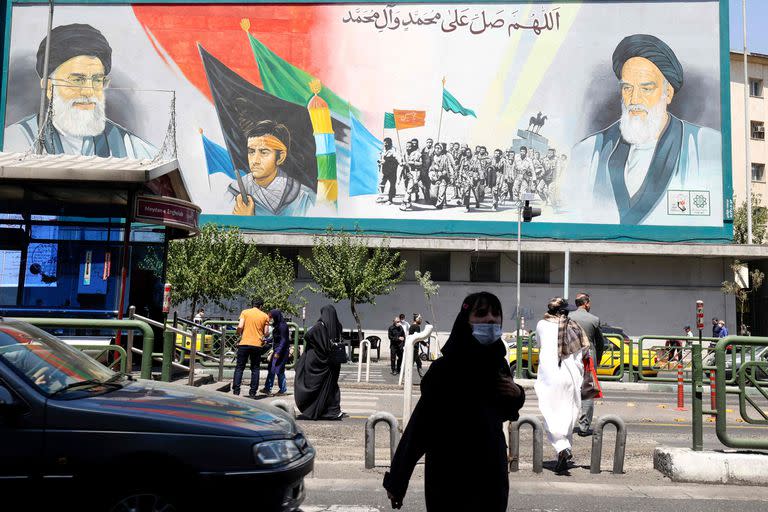 Iraníes caminan junto a un cartel del ayatollah Ali Khamenei (izquierda) y el líder de la Revolución Islámica, Ruhollah Khomeini (derecha) (ATTA KENARE / AFP)