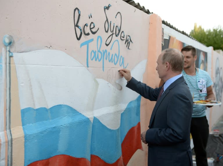 Russian President Vladimir Putin writes his signature on a graffiti at a youth educational forum in Crimea on August 19, 2016