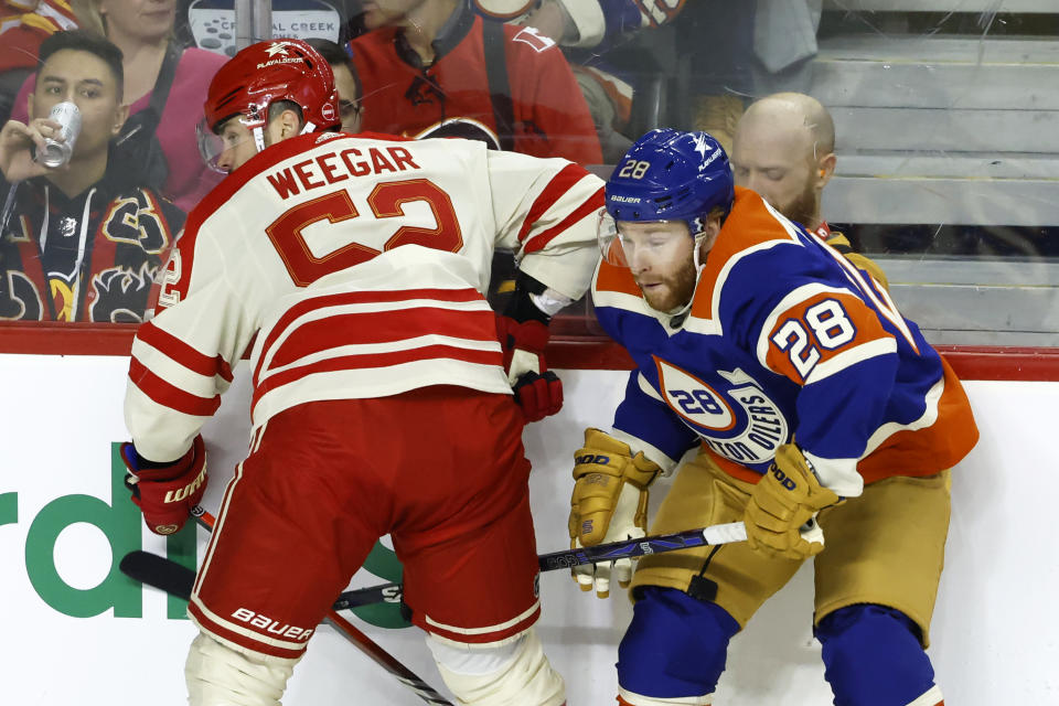 Edmonton Oilers' Connor Brown, right, takes a hit from Calgary Flames' MacKenzie Weegar during the second period of an NHL hockey game Saturday, Jan. 20, 2024, in Calgary, Alberta. (Larry MacDougal/The Canadian Press via AP)