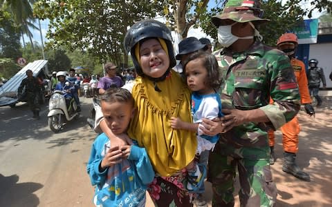 An Indonesian woman cries next to her children shortly after an aftershock hits the area in Tanjung on Lombok island on August 9 - Credit: ADEK BERRY/ AFP