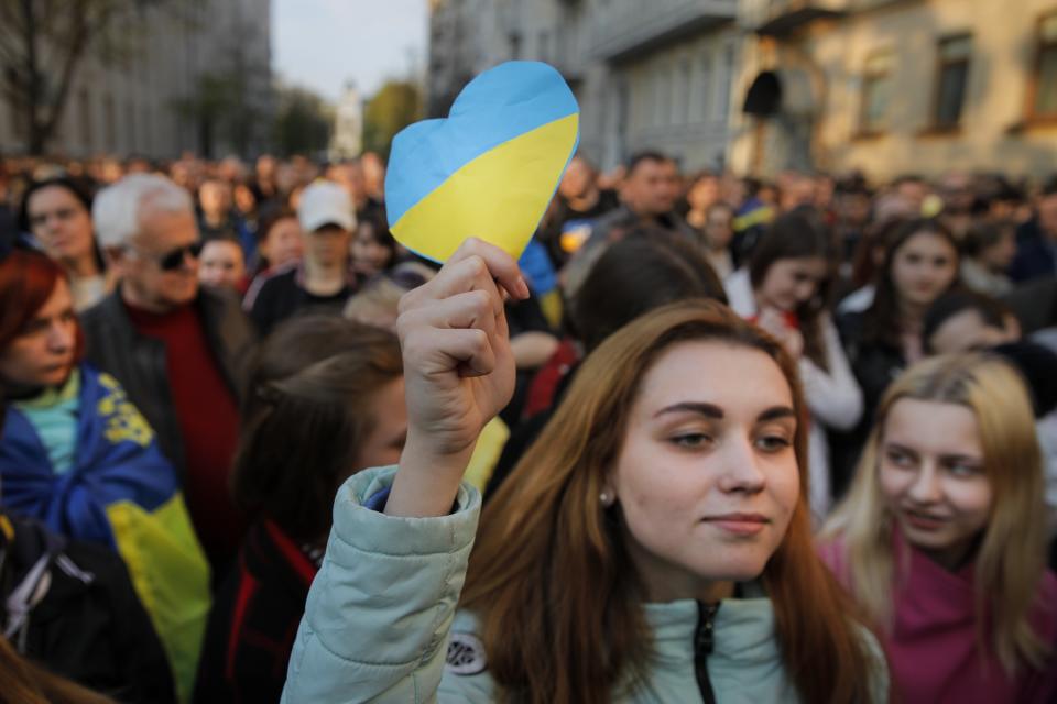 A supporter of Ukrainian President Petro Poroshenko, who have comes to thank him for what he did as a president, holds a cardboard heart with the colors of the Ukrainian national flag listens to his speech in Kiev, Ukraine, Monday, April 22, 2019. Political mandates don't get much more powerful than the one Ukrainian voters gave comedian Volodymyr Zelenskiy, who as president-elect faces daunting challenges along with an overwhelming directive to produce change. (AP Photo/Vadim Ghirda)