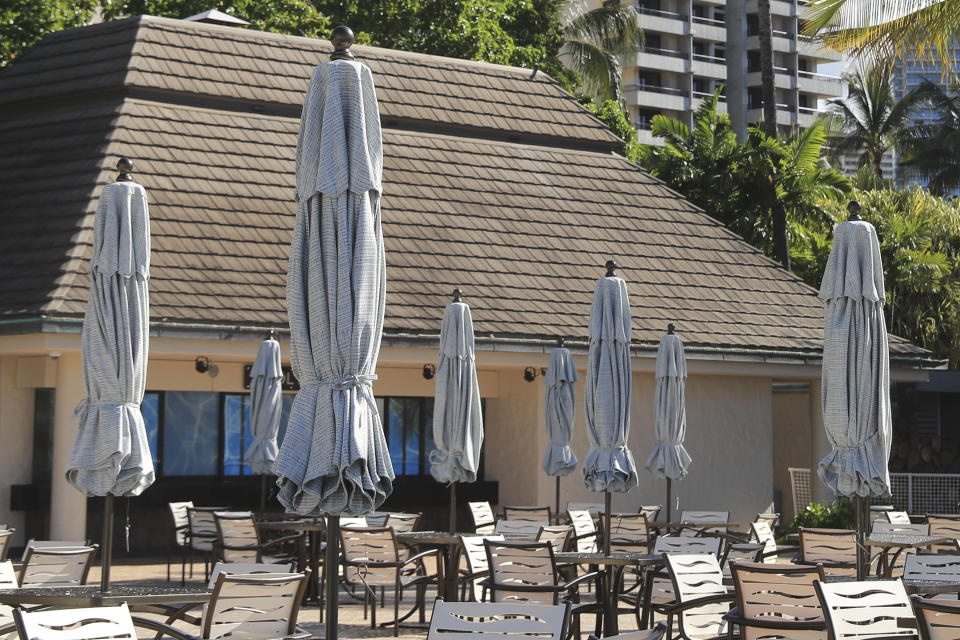 Umbrellas remain closed at an outdoor restaurant on a popular resort in Waikiki, Thursday, Oct. 15, 2020, in Honolulu. A new pre-travel testing program will allow visitors who test negative for COVID-19 to come to Hawaii and avoid two weeks of mandatory quarantine goes into effect Thursday. The pandemic has caused a devastating downturn on Hawaii's tourism-based economy and many are hoping the testing will help the economy rebound. (AP Photo/Marco Garcia)