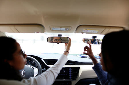 Trainee Maria al-Faraj (L) adjusts a mirror during a driving lesson with instructor Ahlam al-Somali at Saudi Aramco Driving Center in Dhahran, Saudi Arabia, June 6, 2018. REUTERS/Ahmed Jadallah