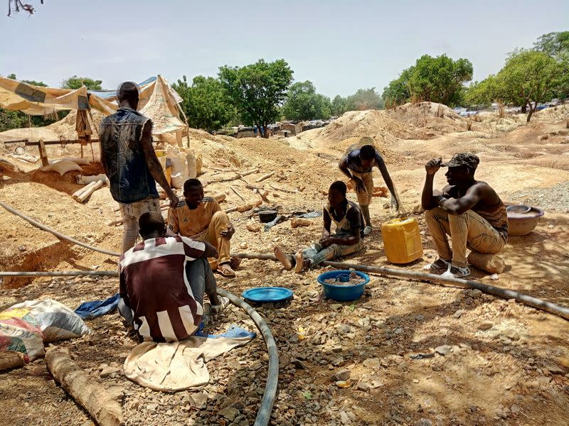 Informal gold miners are seen taking a break from work under the midday sun at an artisanal mining site near Dano