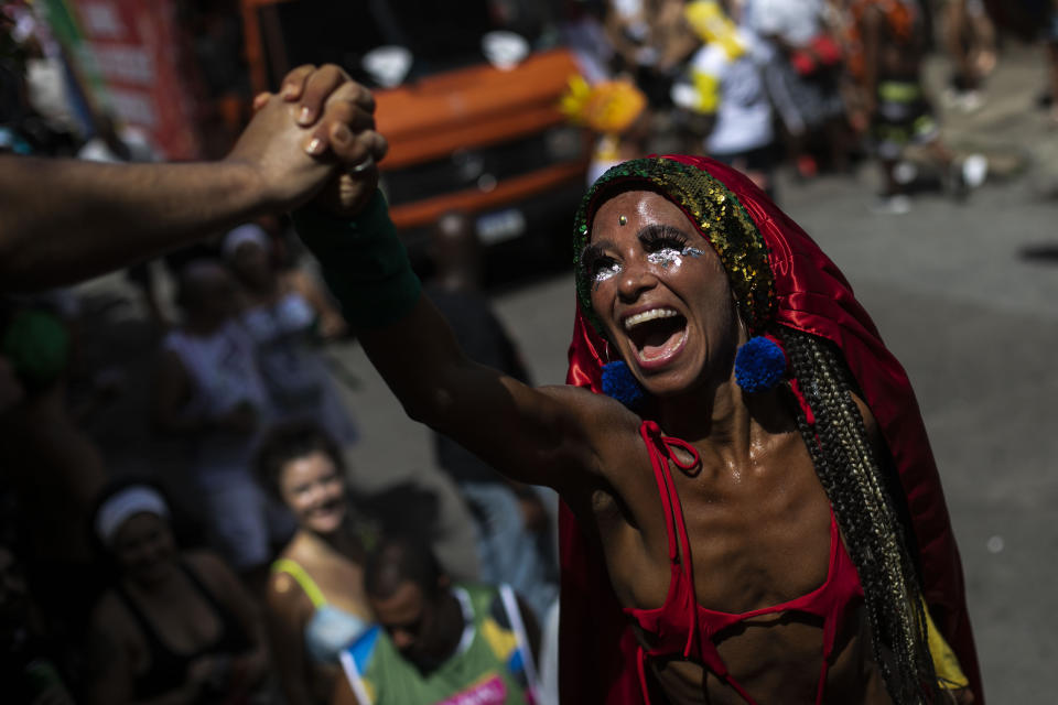 A costumed reveler on stilts greets a spectator during the Carmelitas street party on the first day of Carnival in Rio de Janeiro, Brazil, Friday, Feb. 17, 2023. (AP Photo/Bruna Prado)