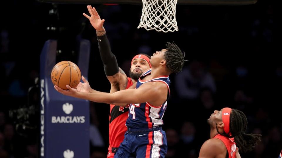 Nets Cam Thomas underhand shot against Raptors blue jersey