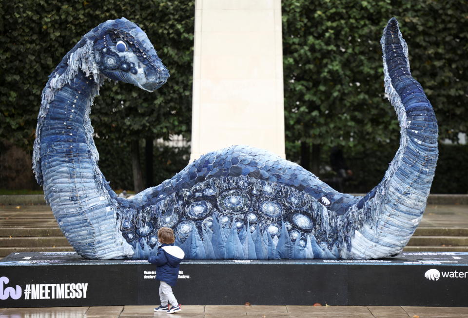 A child walks past 'Messy the COP Ness Monster', a sculpture made with recycled jeans, in Grosvenor Square, London, Britain, October 30, 2021. REUTERS/Henry Nicholls