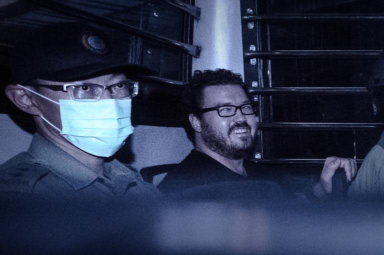 British banker Rurik Jutting, charged with the grisly murders of two women, smiles as he sits in a prison van leaving court in Hong Kong on November 10, 2014