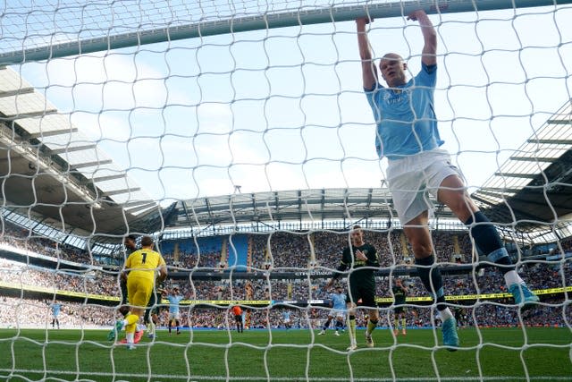 Manchester City striker Erling Haaland (right) hangs on the goalframe against Brentford