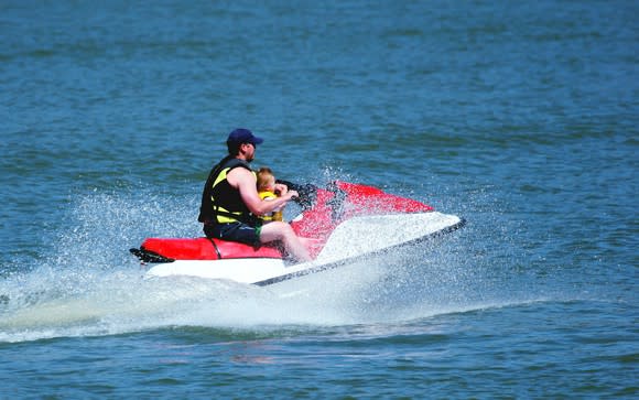 A father and his son on a jet ski in the ocean.