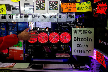 A customer checks the heat generated by a cryptocurrency mining computer equipped with four cooling fans at a computer mall in Hong Kong, China January 29, 2018. Picture taken January 29, 2018. REUTERS/Bobby Yip