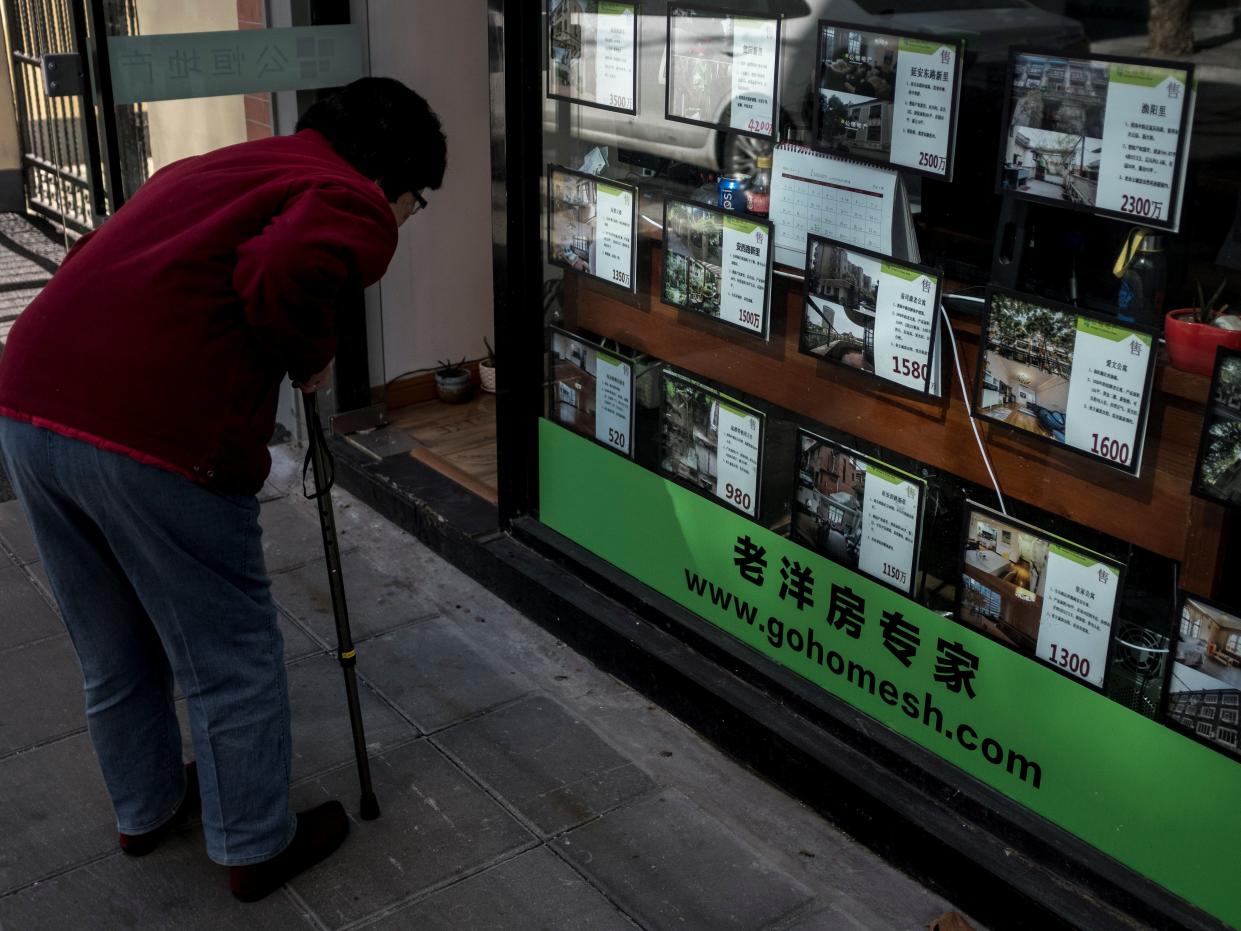 An elderly woman looks at the price tags of houses at a local real estate office in downtown Shanghai on February 12, 2018.