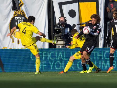 Oct 25, 2015; Columbus, OH, USA; Columbus Crew SC defender Michael Parkhurst (4) sends a clearing ball into D.C. United midfielder Nick DeLeon (14) at MAPFRE Stadium. Mandatory Credit: Greg Bartram-USA TODAY Sports