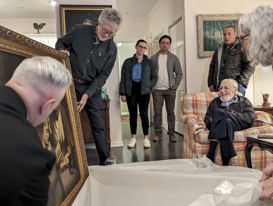 Siblings Tom Wood and Penelope Kulko assist Special Agent Gary France unveil a recovered painting to Dr. Francis Wood in Newark, N.J., on Thursday, Jan. 11, 2024. The 18th-Century John Opie painting stolen by mobsters in 1969 with help from a New Jersey state lawmaker has been returned more than 50 years later, the FBI’s Salt Lake City field office announced Friday, Jan. 26. (FBI via AP)