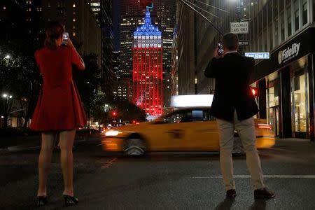 A couple photograph The Helmsley Building on Park Avenue, lit in honor of the victims of the Nice attacks, in Manhattan, New York, U.S., July 15, 2016. REUTERS/Brendan McDermid