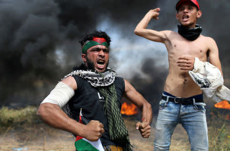 Palestinian protesters react during clashes with Israeli troops at the Israel-Gaza border, in the southern Gaza Strip April 2, 2018. REUTERS/Ibraheem Abu Mustafa