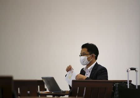 A passenger wearing a mask to prevent contracting Middle East Respiratory Syndrome (MERS) uses his laptop at Gimpo International Airport in Seoul, South Korea, June 17, 2015. REUTERS/Kim Hong-Ji