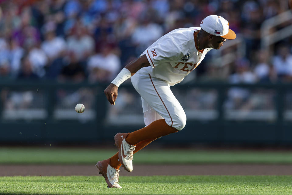 Texas shortstop Trey Faltine (0) loses the ball while trying to throw to first in the fourth inning against Notre Dame during an NCAA College World Series baseball game Friday, June 17, 2022, in Omaha, Neb. (AP Photo/John Peterson)