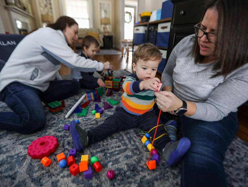 Macklan Trainor, 1, gets help from mom Sally Trainor placing his blocks through a string while playing in the living room with his mom  Leanne Trainor, 42, and brother Gabriel, 4, at their home in Plymouth, Michigan, on Saturday, Feb. 4, 2023. Michigan's family law leaves non-biological LGBTQIA2S+ parents in a murky legal situation where their parental rights to a child could be threatened. In some instances, the parent who is not biologically related to their child pursues a step- or second parent adoption to enshrine their parental rights, like the Trainors did. But it's costly, draining, and insulting to parents who say Michigan's antiquated laws don't reflect the current reality of who becomes a family. Sally and Leanne Trainor each gave both to one of their sons and adopted the other to ensure parental rights that don't naturally come to heterosexual parents that have children together.