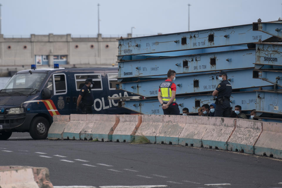 Police officers detain migrants who tried to reach the Spanish Peninsula by ferry, in Santa Cruz de Tenerife, Spain, Sunday, March 21, 2021. While Spain has been critical of its European neighbours' lack of solidarity when it comes to sharing the responsibility of migration, the country is similarly being criticized by migrants, authorities and human rights organizations on the Canary Islands where some 23,000 people arrived by sea last year and where many thousands remain on the island forcefully. (AP Photo/Joan Mateu)