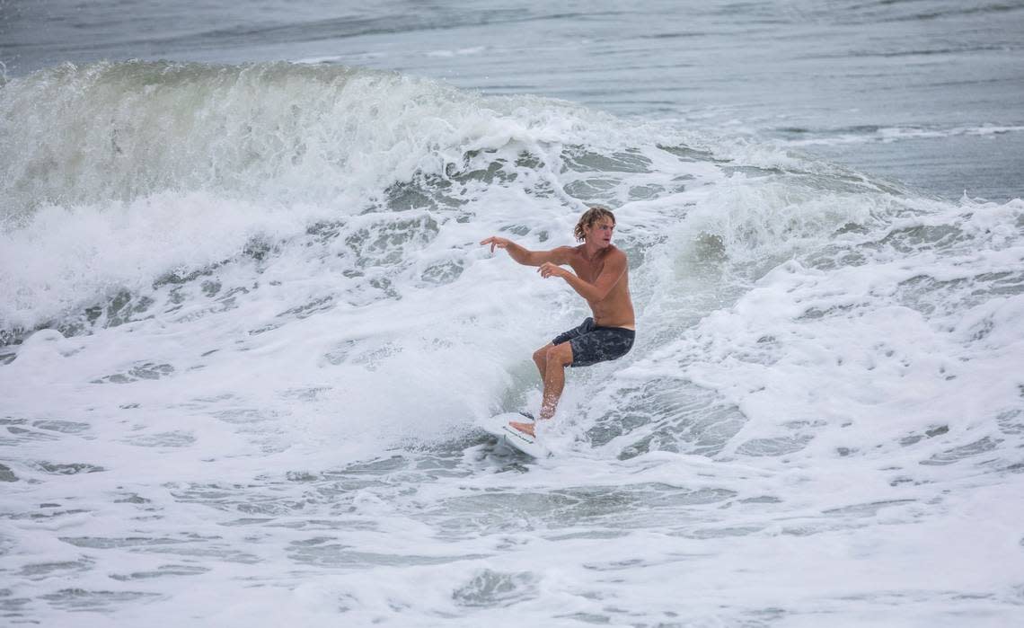 A surfer rides out of a wave in swells brought on by Tropical Storm Isaias near Bogue Inlet Pier in Emerald Isle, N.C. on Monday evening, Aug. 3, 2020.