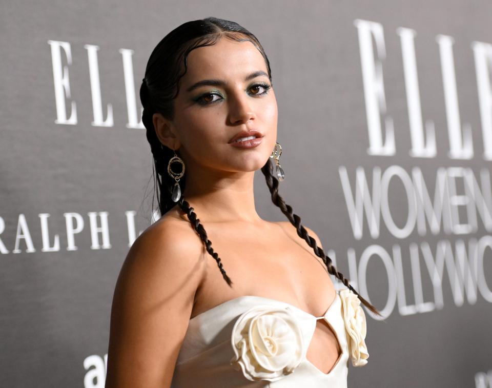 Isabela Merced in an elegant outfit with braided hair and a floral accent posing at the ELLE Women in Hollywood event