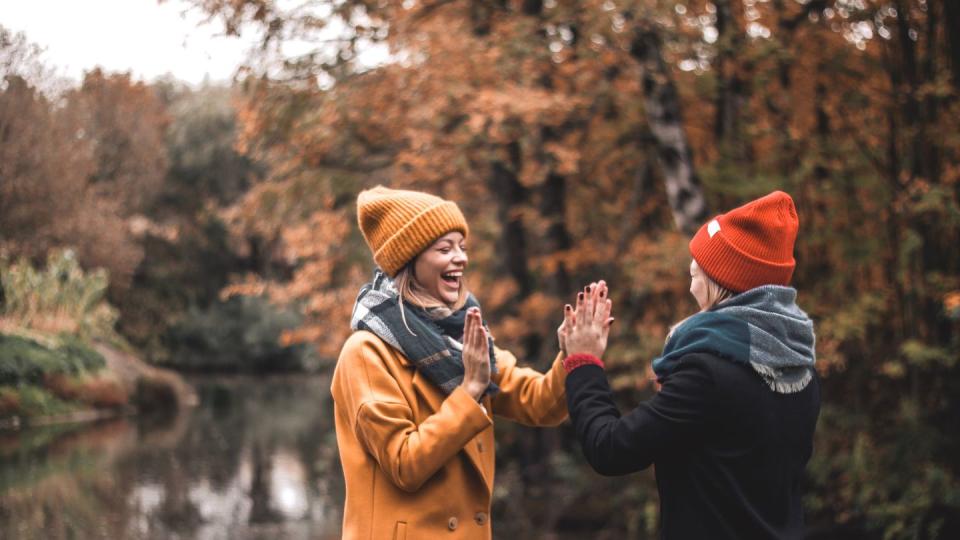 two friends high fiving at fall lake