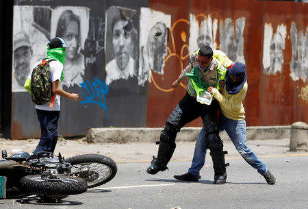 A demonstrator grabs a riot police officer at a rally against Venezuela's President Nicolas Maduro's government in Caracas, Venezuela April 10, 2017. REUTERS/Christian Veron