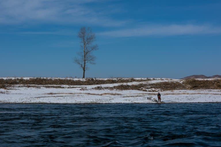 A North Korean woman stands on the bank of the Yalu river