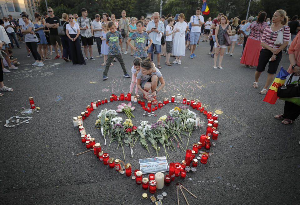 People light candles outside the government headquarters in memory of a 15 year-old girl, raped an killed in southern Romania, after police took 19 hours from the moment she called the country's emergency hotline to intervene, in Bucharest, Romania, Saturday, July 27, 2019. Thousands of people took part Saturday evening in Bucharest in a march protesting the handling of the case, blaming Romanian officials for negligence, incompetence and a lack of empathy. (AP Photo/Vadim Ghirda)