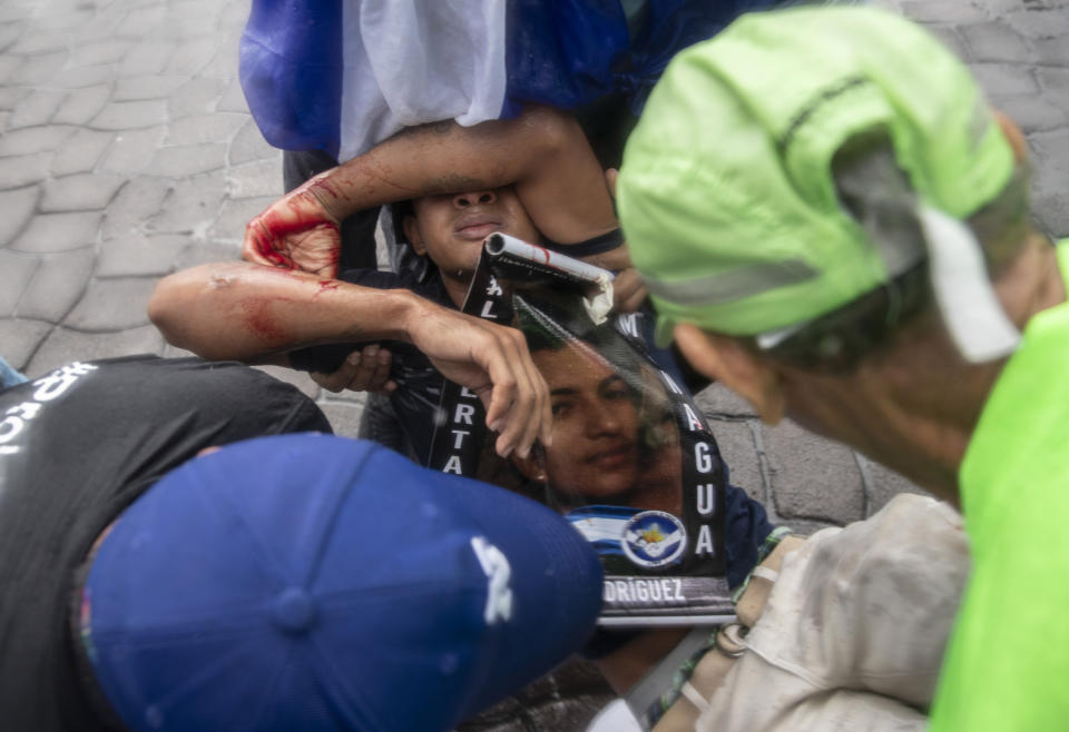 People come to the aid of a young protester who was injured by a stun bomb launched by police to disperse demonstrators at an anti-government march dubbed, "Nothing is Normal” in honor of slain student Matt Romero, in Managua, Nicaragua, Saturday, Sept. 21, 2019. 16-year-old Matt Romero was killed during “crossfire” last September when armed men wearing hoods clashed with anti-government protesters. (AP Photo/Alfredo Zuniga)