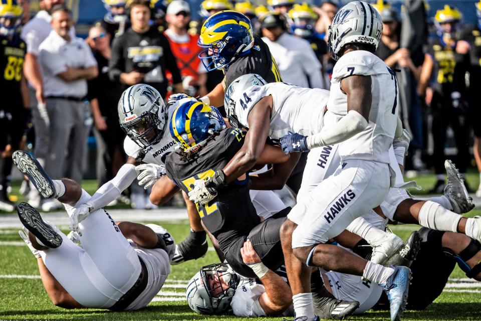 Delaware Blue Hens Khory Spruill (22) hangs on to the ball as CAA newcomer the Monmouth Hawks' Ryan Moran (55), on the bottom, and Ben Joseph (44) take him down during the football game at Delaware Stadium, Saturday, Nov. 5, 2022. Delaware won 49-17.