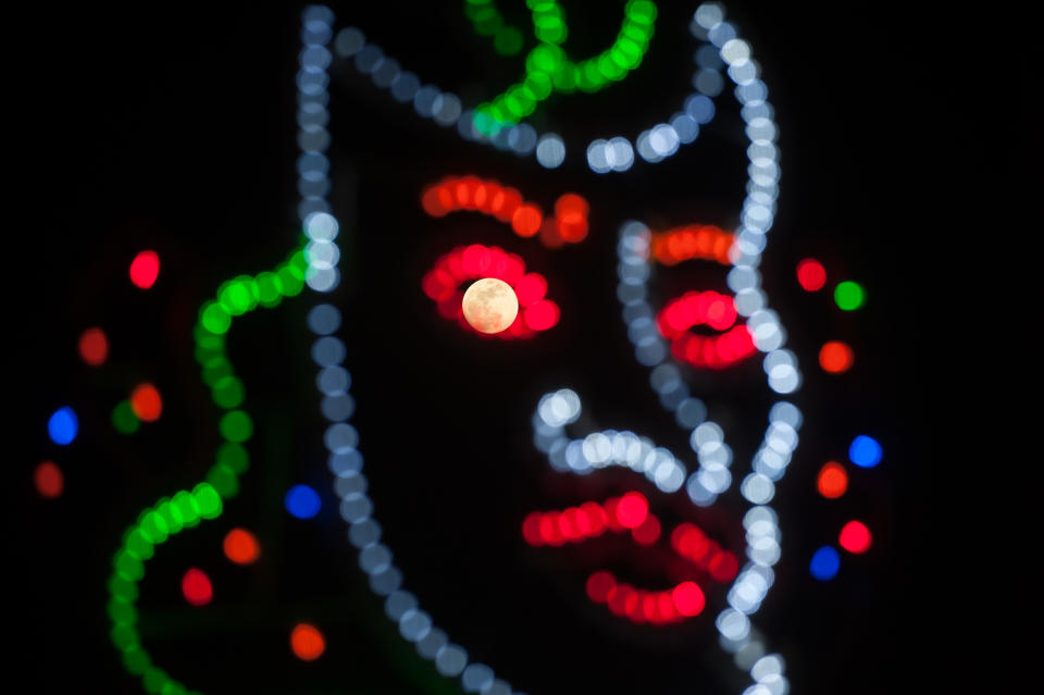 <p>A ‘super moon’ is seen on the sky trough a carnival lighting mask in Malaga, Spain, Jan. 30, 2018. (Photo: Jesus Merida/SOPA Images/LightRocket via Getty Images) </p>