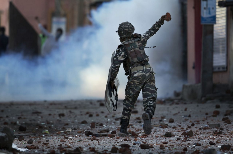 Ein paramilitärischer Soldat in Srinagar wirft Ziegelsteine gegen Demonstranten. In der von Indien besetzten Kaschmir-Region herrscht seit Wochen Anspannung, nachdem ein islamistischer Anführer aus Pakistan von der Polizei getötet wurde. (Bild: Dar Yasin/AP)