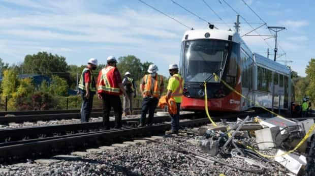 People examine the O-Train tracks near where a light rail train derailed at Tremblay station in Ottawa this past Sunday. (Jean Delisle/CBC - image credit)