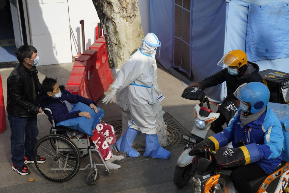 A medical worker in protector overall escorts a patient in wheelchair from the fever screening department of the Tongji Hospital which was at the frontline of the China's fight against the coronavirus in Wuhan in central China's Hubei province on Friday, Jan. 15, 2021. The WHO team of international researchers that arrived in the central Chinese city of Wuhan on Thursday hopes to find clues to the origin of the COVID-19 pandemic. (AP Photo/Ng Han Guan)
