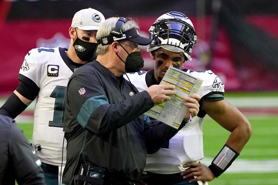 Philadelphia Eagles head coach Doug Pederson talks with starting quarterback Jalen Hurts as quarterback Carson Wentz (11) looks on during the first half of an NFL football game, Sunday, Dec. 20, 2020, in Glendale, Ariz. (AP Photo/Rick Scuteri)