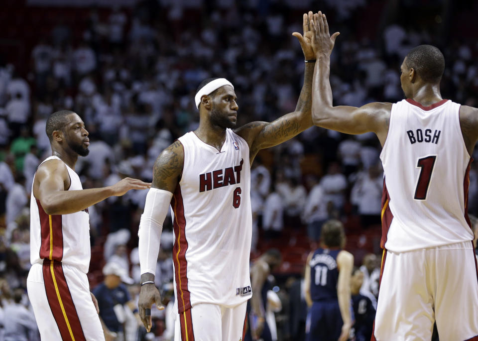 Miami Heat's LeBron James (6) high-fives Chris Bosh (1) after the Heat defeated the Charlotte Bobcats 101-97 in Game 2 of an opening-round NBA basketball playoff series, Wednesday, April 23, 2014, in Miami. At left is Dwyane Wade. (AP Photo/Lynne Sladky)