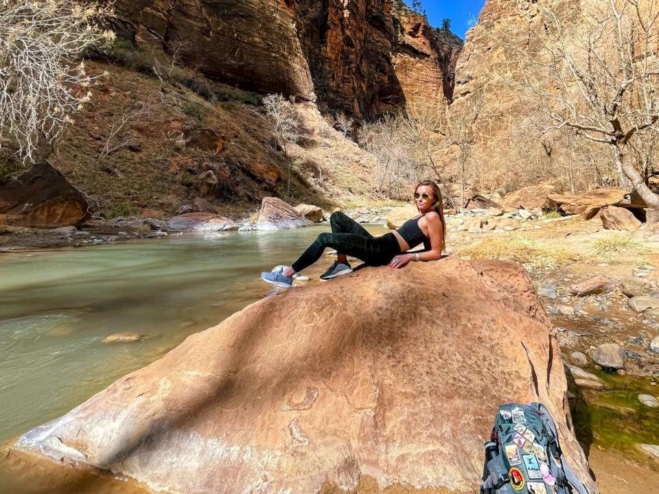 Emily lying on a rock in front of a body of water at Zion National Park.